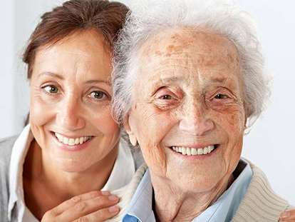 lächelnde Seniorin mit ihrer Pflegerin